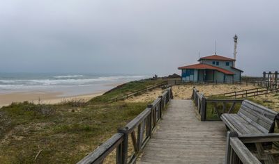 a wooden walkway leading to a beach with a life guard tower in the background