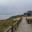 a wooden walkway leading to a beach with a life guard tower in the background
