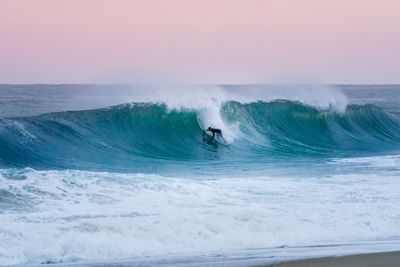 Surfer on a big wave in Hossegor. Pink sky and ocean dream